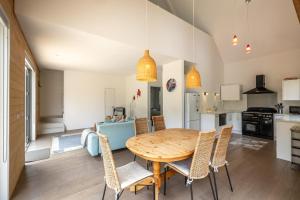 a kitchen and dining room with a wooden table and chairs at Boathouse Onetangi - Stay Waiheke in Waiheke Island
