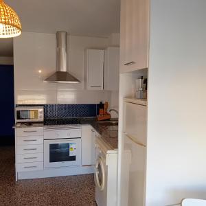 a kitchen with white cabinets and a washer and dryer at María PLAYA 1 NG in Peniscola