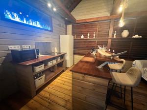 a kitchen with a counter with a refrigerator and chairs at Lodge Eden, SPA Privatif in Les Abymes +25 photos