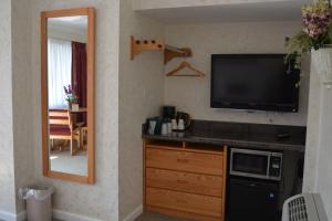 een woonkamer met een televisie en een spiegel bij Travelers Inn in South San Francisco