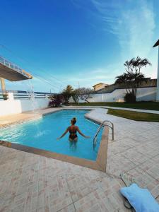 a woman is standing in a swimming pool at Hospedagem no Ônibus Navy na Praia da Baleia - Jacaraípe in Serra