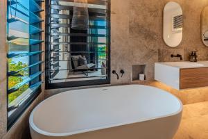 a bathroom with a tub and a sink and a window at Haven House at Hamilton Island in Hamilton Island +34 photos