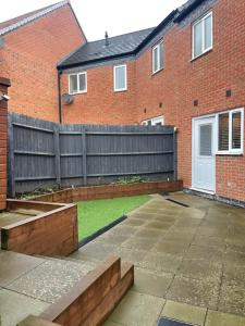 a garden with a wooden fence and a house at Nuneaton Pink Rose in Stockingford