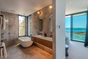 a bathroom with a tub and a toilet and a sink at Haven House at Hamilton Island in Hamilton Island