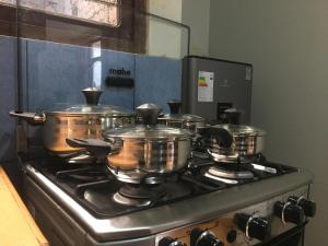 vier Töpfe und Pfannen auf einem Herd in einer Küche in der Unterkunft Depa en 1er piso,cochera, close to the plaza and UNSCH in Ayacucho