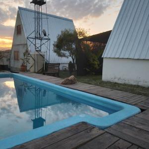 una piscina accanto a un fienile con riflesso nell'acqua di Cabañas Alpinas M y M a Bialet Massé