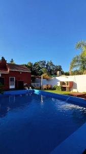 Una gran piscina azul frente a una casa en La Quintita, en Villa Elisa