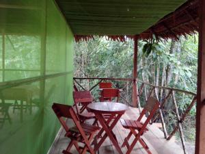 una mesa y sillas en el porche de una casa verde en Amazon Golden Snake Lodge, en Santa Teresa