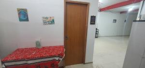 a room with a bed and a wooden door at Quarto com cozinha funcional in Guarapari