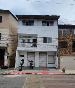 a white house with a motorcycle parked in front of it at Quarto com cozinha funcional in Guarapari