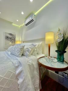 een slaapkamer met een wit bed en een tafel met een lamp bij Top of the Alpha Duplex in Barueri
