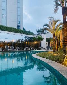 een zwembad met palmbomen en een gebouw bij Top of the Alpha Duplex in Barueri