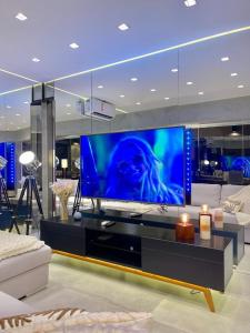 een groot scherm tv in een woonkamer met een bank bij Top of the Alpha Duplex in Barueri