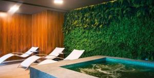 een kamer met een groene muur met stoelen en een zwembad bij Top of the Alpha Duplex in Barueri