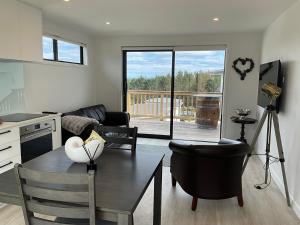 un salon avec une table et des chaises et une cuisine dans l'établissement Nautilus self-catering cottage, à Maraetai