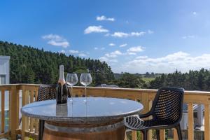 - une table avec deux verres de vin sur une terrasse dans l'établissement Nautilus self-catering cottage, à Maraetai 2 autres photos