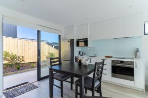 - une cuisine avec une table et des chaises noires dans la chambre dans l'établissement Nautilus self-catering cottage, à Maraetai