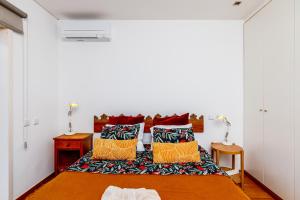 a bedroom with a bed with colorful pillows on it at Lisbon Casa da Clementina - a Serene Garden Stay in Lisbon