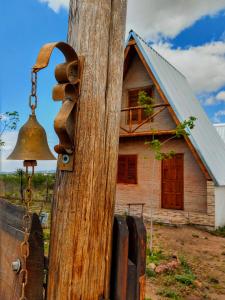 eine alte Glocke an einem Holzpfosten mit einem Haus in der Unterkunft Cabañas Alpinas M y M in Bialet Massé + 19 Fotos