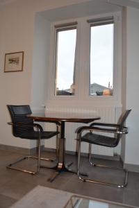 a table and two chairs in a room with two windows at Appartement-terrasse parking privé Meublé de Tourisme 4 étoiles in Belfort
