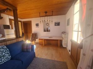 un salon avec un canapé bleu et une table dans l'établissement La Chanterelle Apartment, à Morzine