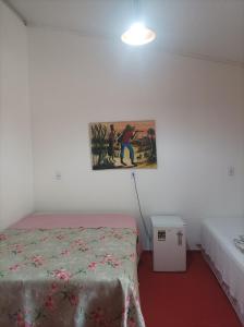 a bedroom with a bed and a painting on the wall at Siete aconchego in Porto Seguro