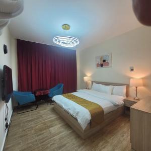Habitación de hotel con cama y cortina roja en Sun Rose Apartment, en King Abdullah Economic City