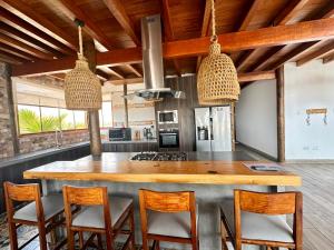 una cocina con una gran isla de madera con sillas en Refugio del Mar Wakama, en San Vicente de Cañete