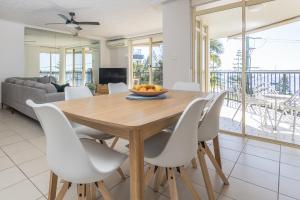 Un comedor con una mesa de madera y sillas blancas. en Bayview Beach Holiday Apartments, en Gold Coast