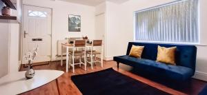 ein Wohnzimmer mit einem blauen Sofa und einem Tisch in der Unterkunft Charming 3-Bedroom Home Near NEC, Birmingham Airport & Bullring in Birmingham