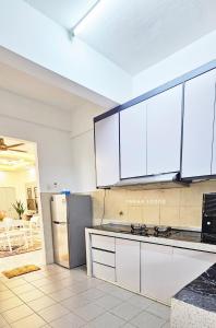 a kitchen with white cabinets and a stainless steel refrigerator at Tara Lodgemuslim Homestay Putrajaya in Putrajaya