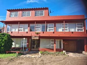 un edificio rojo con un banco delante de él en Hotel Monte Castello, en Villa Gesell