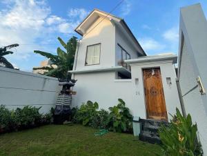 a white house with a wooden door in a yard at LaJimbar Villa Sanur Bali in Ketewel