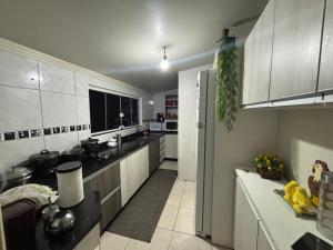 una cucina con mobili bianchi e un frigorifero di Casa temporada Passo de Torres a Passo De Torres