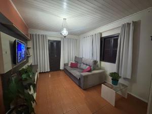 un soggiorno con un divano e una TV di Casa temporada Passo de Torres a Passo De Torres