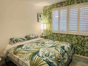 a bedroom with a large bed with a tropical wallpaper at 2 bedroom Beach cafes shops bus all a walk away in Deewhy