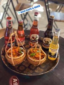 a tray with bottles of beer and baskets of food at Ban Urban House in Buon Ma Thuot