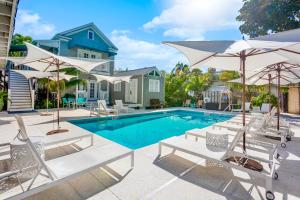 a pool with chairs and umbrellas in front of a house at Eden House in Key West