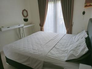 Una cama blanca en una habitación con ventana. en Wihmo Villa Bali, en Nusa Dua