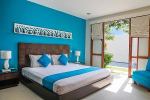 a bedroom with a large bed and a blue wall at Samana Villas in Legian