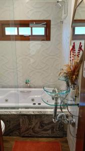 La salle de bains est pourvue d'une table en verre à côté d'une baignoire. dans l'établissement Pousada CHÂTEAU LUMIÈRE, à Itaara