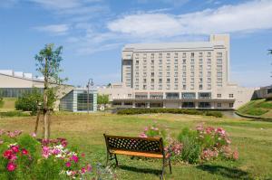 un banco del parque frente a un gran edificio en Hotel Arrowle en Kaga