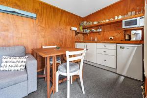une petite cuisine avec une table et un canapé dans l'établissement Onaeros Cute Little Cottages - Taranaki Retreat, à Waitara 36 autres photos