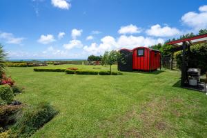 un hangar rouge dans une cour avec une pelouse verte dans l'établissement Onaeros Cute Little Cottages - Taranaki Retreat, à Waitara
