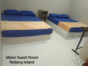 a bedroom with two beds and a chair at Melor Guest house in Kampong Telok Dalam