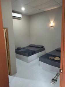 two beds in a white room with a mirror at Melor Guest house in Kampong Telok Dalam
