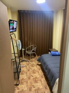 a bedroom with a bed and a chair and a television at Family Home Furnished Centro Chincha Alta in Chincha Alta