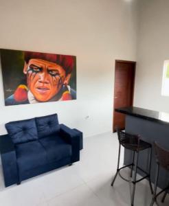 a living room with a blue couch and a painting at Casa good vibes in Pipa