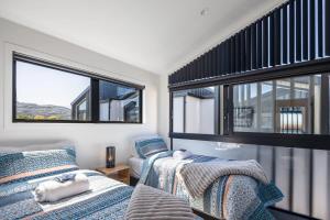 two beds in a room with two windows at Dreamcatcher Cottage - 2BR Mystic Moonrise in Lower Hutt