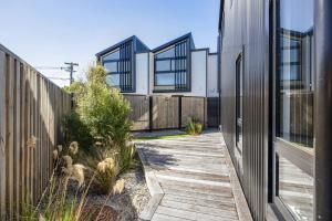 a house with a wooden walkway between two buildings at Dreamcatcher Cottage - 2BR Mystic Moonrise in Lower Hutt